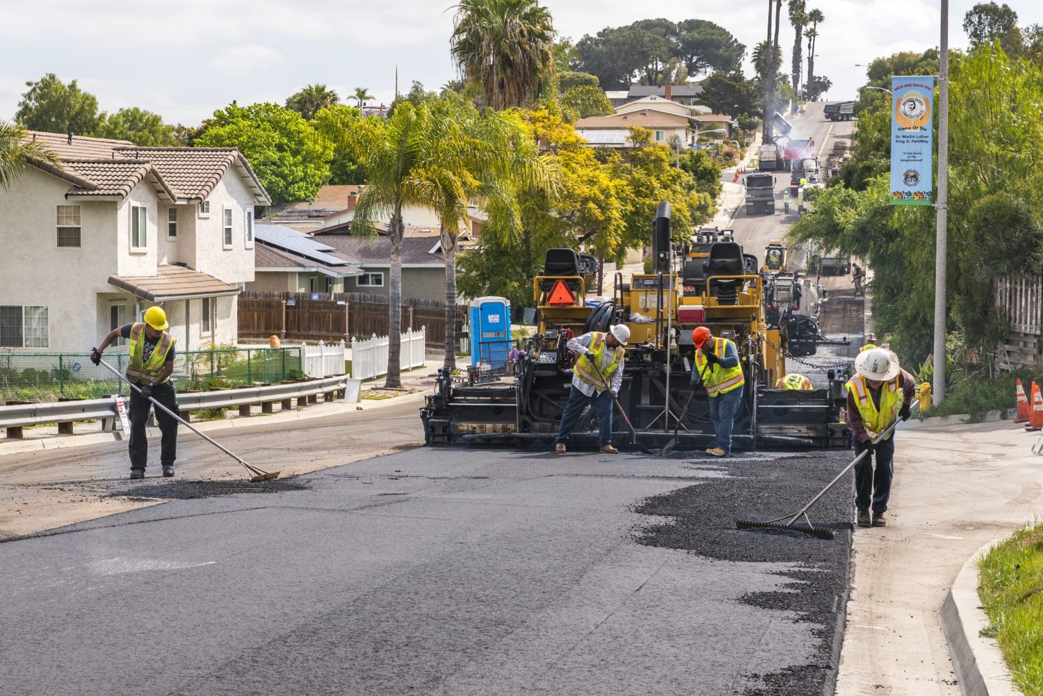 UUD Street Resurfacing & Curb Ramp Installation paving crew applying asphalt on hill in neighborhood