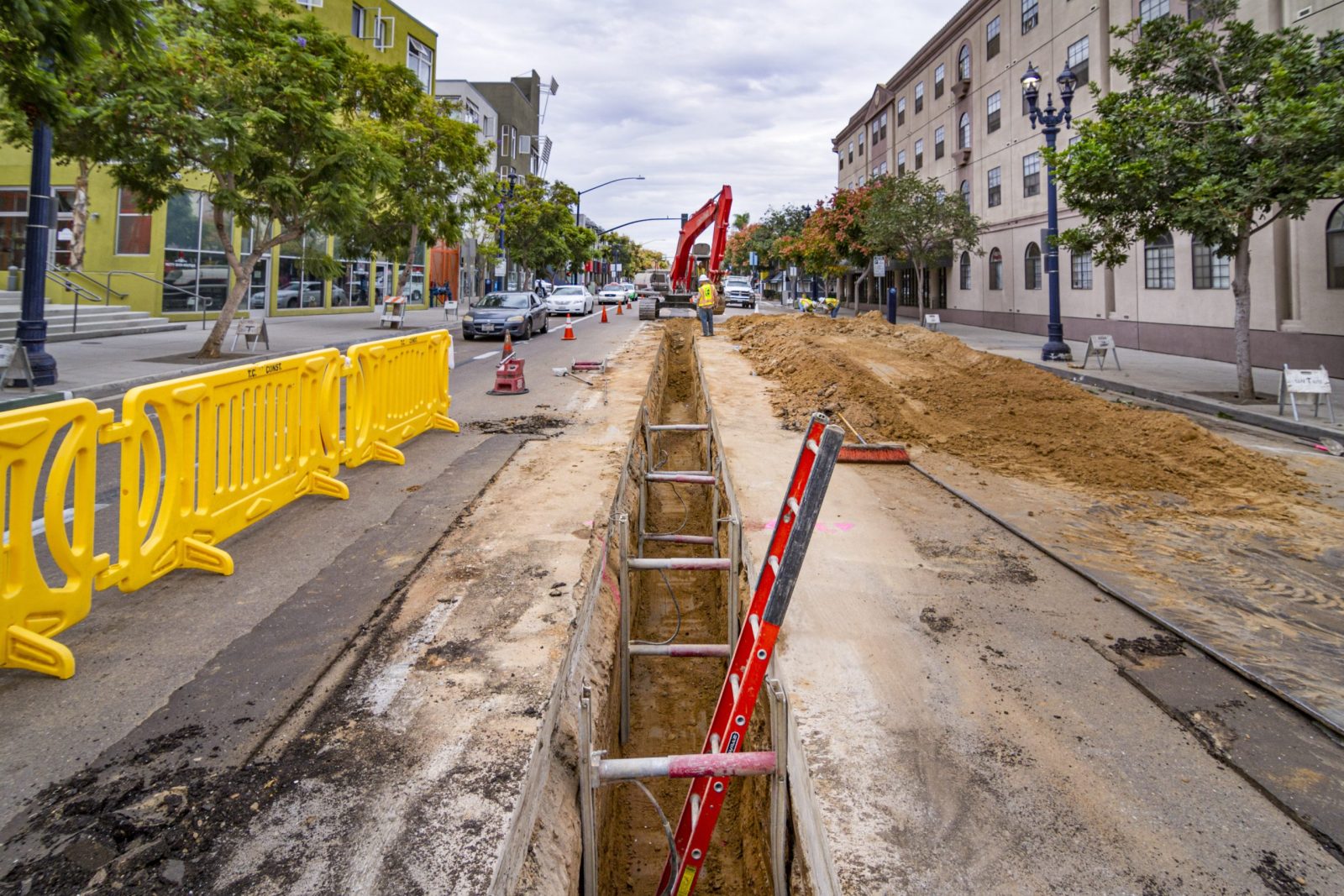 13-027 Sewer and Water Group 957, machinery and crew excavating deep trench in busy commercial district