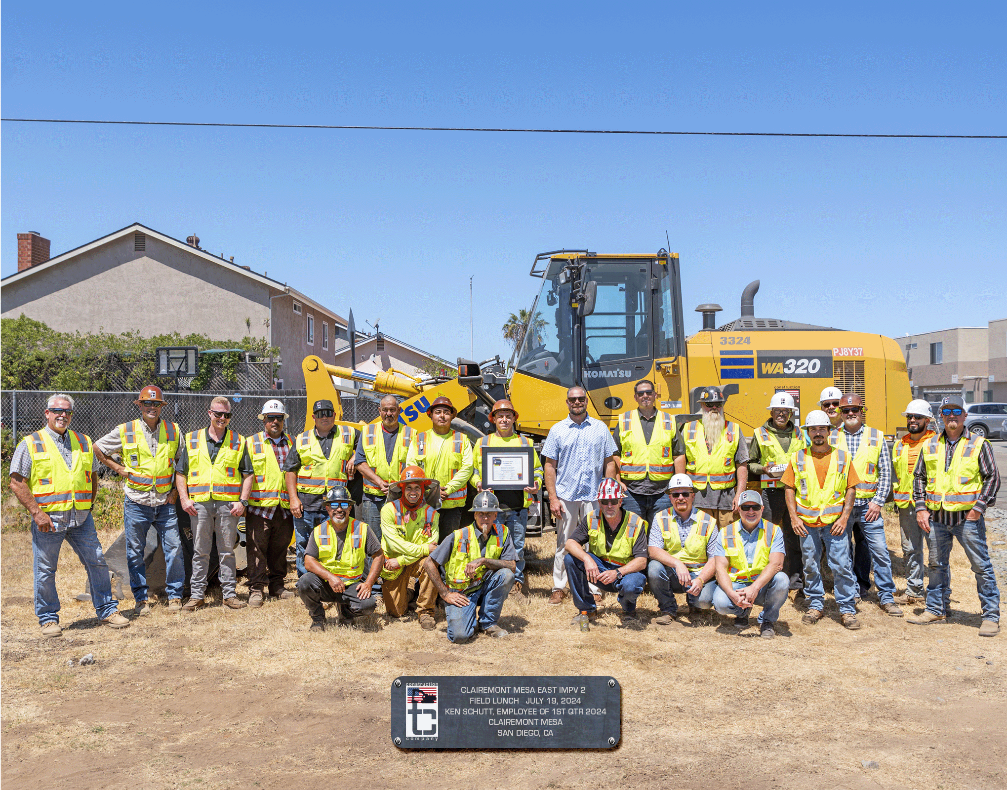 Group photo of crew in front of loader machine on jobsite