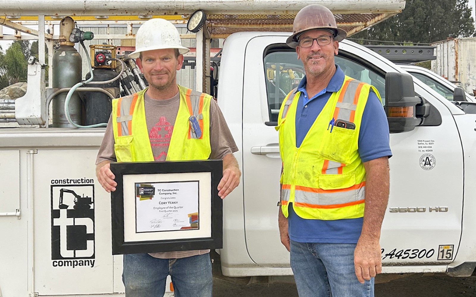 Forman Rick Dickerson giving Employee of the Quarter award to Cory Yeakey on construction site