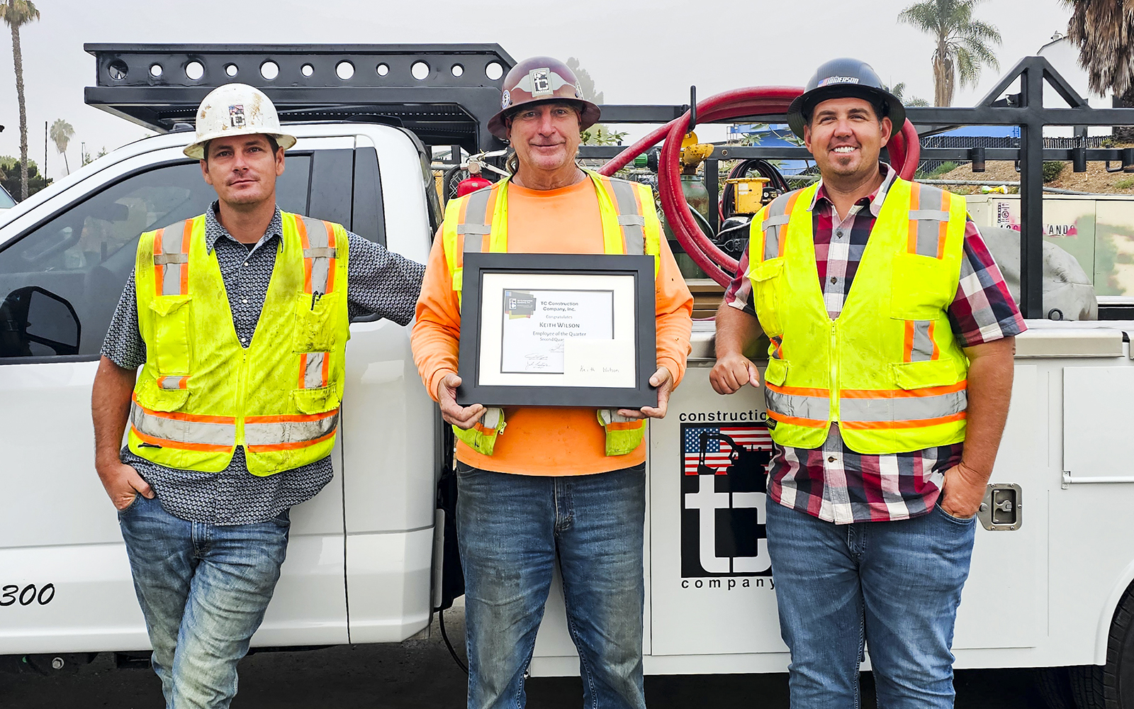 Forman Jordan Meyer and Superintendent Rocky Anderson giving Employee of the Quarter award to Keith Wilson on construction site